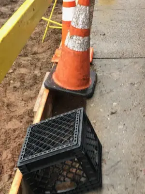 Timber edge form and traffic cone beside the sidewalk.