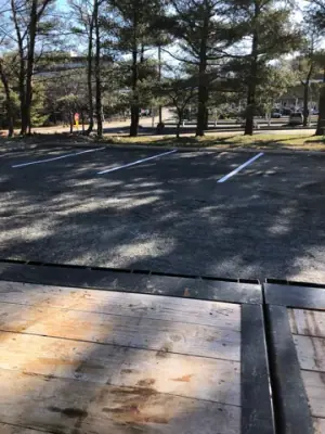 Striped parking spaces along the tree-lined property boundary.