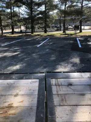 Striped parking spaces along the tree-lined property boundary.