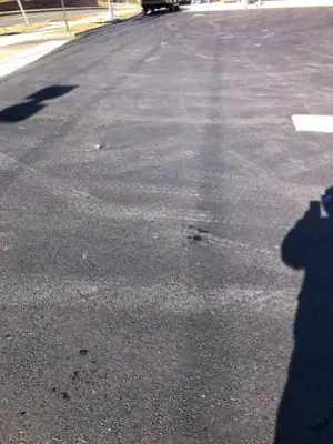 Asphalt surface and flush access cover in the drive aisle.