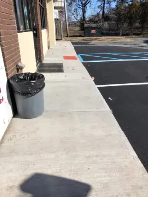 Concrete storefront walkway beside the marked parking spaces.